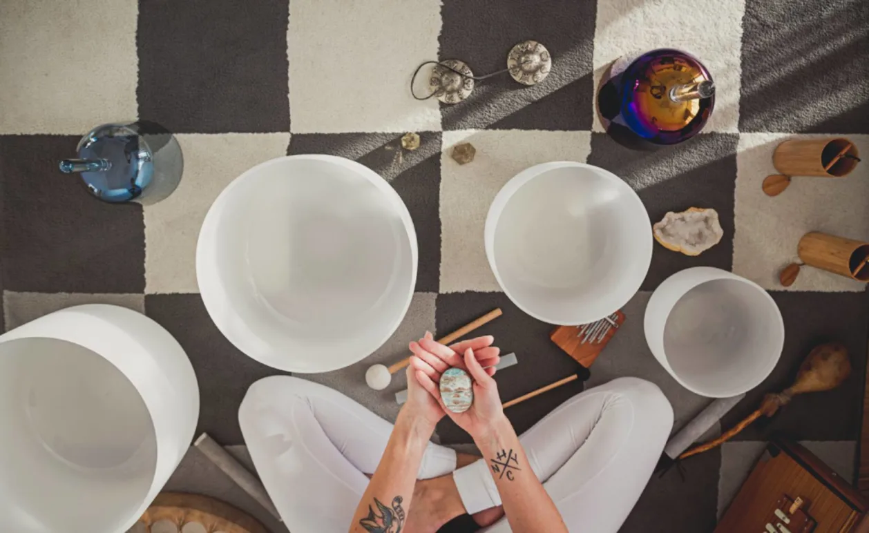 Woman holding calcite above crystal singing bowls